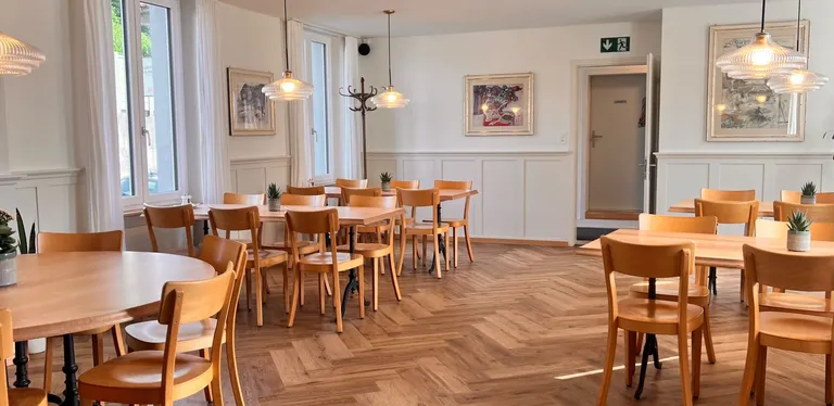 Heller Speisesaal mit Parkettboden und gedeckten Tischen